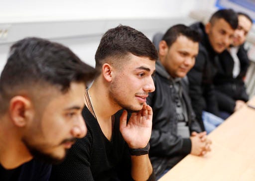 In this Nov. 22, 2016 photo Essam Kadib al Ban, second from left, takes part in a flirt workshop for refugees in Dortmund, Germany. Horst Wenzel, who usually teaches German men how to approach women, volunteers his skills to help with integrating some of the more than 1 million refugees who have arrived over the past two years in Germany. (AP Photo/Michael Probst)