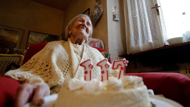 Emma Morano holds a cake with candles marking 117 years in the day of her birthday in Verbania, Italy, Tuesday, Nov. 29, 2016. (AP Photo/Antonio Calanni)