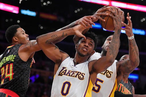 Atlanta Hawks forward Kent Bazemore, left, battles for a rebound with Los Angeles Lakers guard Nick Young, center, and forward Thomas Robinson during the first half of an NBA basketball game Sunday, Nov. 27, 2016, in Los Angeles. (AP Photo/Mark J. Terrill)