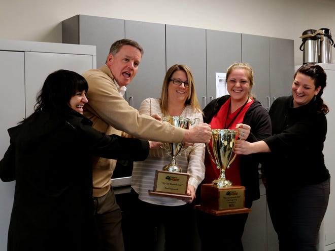 Employees of companies at Pease International Tradeport participate in a friendly tugging of the coveted "My Cup Runneth Over" Pease 'n Carrots Challenge Cup and Most Improved Cup during an official kickoff ceremony of the ninth annual Pease 'n Carrots food drive that benefits the Seacoast Family Food Pantry held Tuesday morning at Sprague Energy. From left, Mary Vinagro of Ipsumm, Tim Winters of Sprague and a board member of SFFP, Jen Rhode of Loftware, team captain Abi Brown of ActivMed Practices & Research, and Siobhan Tetreault of ActivMed. Suzanne Laurent photo