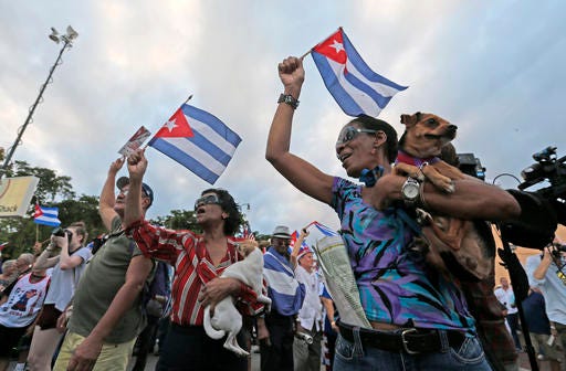 Iris Castillo, right, and her dog Negrito, and Avelina Questa, center, and her dog Chiquitica, dance and wave Cuban flags as they attend a rally, Wednesday, Nov. 30, 2016, in the Little Havana neighborhood of Miami. Hundreds of Cuban exiles in Miami rallied Wednesday for freedom and democracy on the communist island following the death of revolutionary leader Fidel Castro. (AP Photo/Wilfredo Lee)