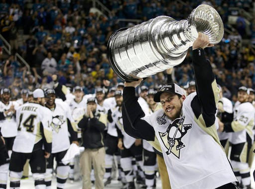 FILE - In this June 12, 2016, file photo, Pittsburgh Penguins center Sidney Crosby raises the Stanley Cup after Game 6 of the NHL hockey Stanley Cup Finals against the San Jose Sharks in San Jose, Calif. In the opening days of training camp, Eric Fehr could sense that the Penguins hadn’t had a lot of rest since winning the Stanley Cup in mid-June. That fatigue affected the runner-up San Jose Sharks more than it did the Penguins early on. But each Cup finalist and the conference finalist Tampa Bay Lightning and St. Louis Blues are again among the best teams in the NHL at the quarter mark of the regular season. (AP Photo/Marcio Jose Sanchez, File)