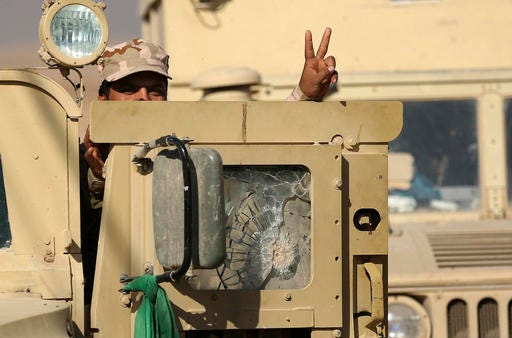 An Iraqi Army soldier flashes a victory sign as he leaves his armored vehicle after a military operation to regain control of a village outside Mosul, Iraq, Tuesday, Nov. 29, 2016. Iraqi forces are assaulting villages far south of Mosul in the Nineveh province, attempting to clear rural areas of Islamic State fighters who stayed behind to hinder their advance. (AP Photo/Hadi Mizban)