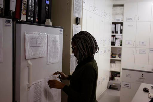 Pharmacist Mary Chindanyika looks at documents on a fridge containing a trial vaccine against HIV on the outskirts of Cape Town, South Africa, Wednesday, Nov. 30, 2016. The latest attempt in the long, frustrating search for a vaccine against HIV began in South Africa on Wednesday, as scientists test a beefed-up version of the only shot ever to show a glimmer of protection. (AP Photo/Schalk van Zuydam)