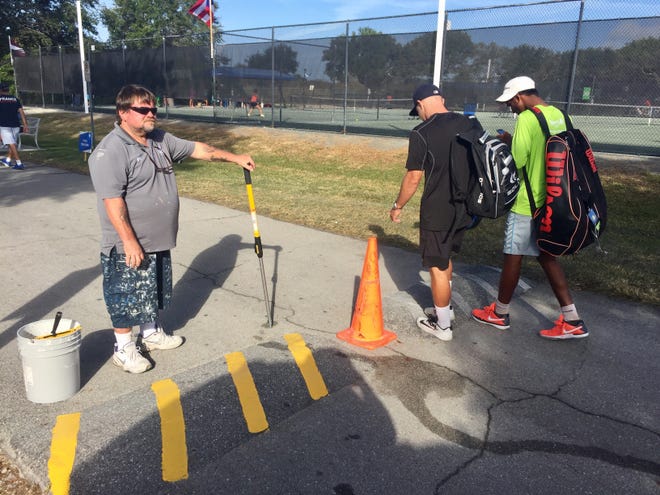 The tennis action at the Eddie Herr International Junior Tennis Championships is so busy that distracted fans seem to keep stumbling across the speed bumps at IMG Academy. On Wednesday, IMG worker Dewey Kinney, left, applied fresh yellow stripes as a precaution. STAFF PHOTO / THOMAS BECNEL