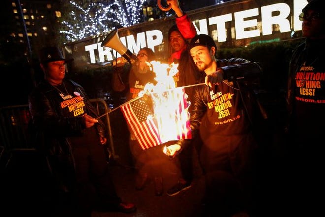 Supporters of the 'NYC Revolution Club' burn the U.S. flag outside the Trump International Hotel and Tower in New York on Nov. 29, 2016, after President-elect Donald trump tweeted that flag-burners should be jailed for forfeit their citizenship.