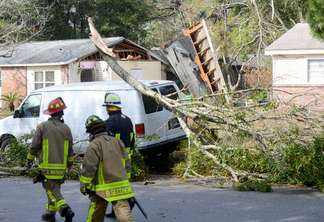 Firefighters walk by a damaged home and trees after a waterspout came ashore on Kohler Drive in Mary Esther. NICK TOMECEK/DAILY NEWS