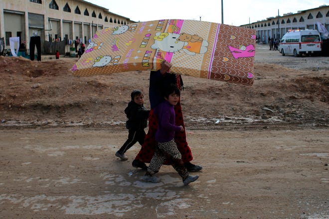 A Syrian woman displaced with her family from eastern Aleppo walks with her children as she carries a mattress in the village of Jibreen south of Aleppo, Syria, Saturday, Dec. 3, 2016. Aid agencies say that more than 30,000 people have fled rebel-held eastern neighborhoods of Aleppo that have been under tight siege since July. Over the past two weeks, government forces launched an offensive in which they regained control of nearly half areas that had been held by insurgents in their deepest push since the city became contested in July 2012.(AP Photo/Hassan Ammar)