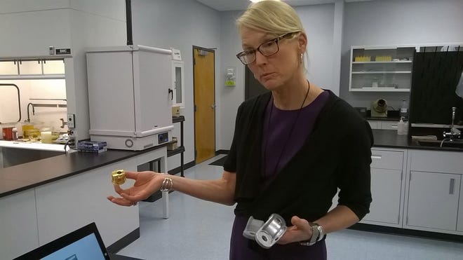 Molly Kellogg, president and CEO of Hubbard-Hall in Inman, shows a brass fitting and aluminum bracket that have been treated with specialty chemicals produced at the Inman facility. The company's applications improve a product's appearance, performance and helps to extend its life.