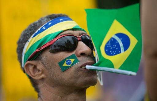 A man holds a Brazil's national flag with his mouth during a protest against corruption on Copacabana beach, in Rio de Janeiro, Brazil, Sunday, Dec. 4, 2016. Thousands of protesters are crowding Rio de Janeiro's beachfront to express disgust with public corruption and to support the judges and prosecutors pursuing those crimes. Protests are also under way Sunday in other Brazilian cities. (AP Photo/Silvia Izquierdo)