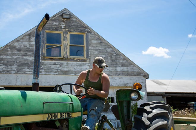 Aaron Sniezek, 16, drives a tractor into a field to bail straw at his family's farm near New Castle in July. Sniezek is a third-generation farmer on his family's 300 acres of wheat, corn, soy, oats and hay.