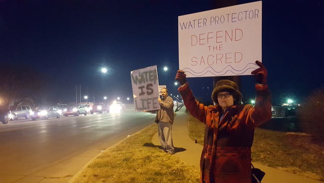 Marsha Cox, right, of Topeka and Jason Fultz, of Auburn, hold signs opposing the Dakota Access Pipeline on Topeka Boulevard near the Kansas River bridge Monday. (Luke Ranker/The Capital-Journal)