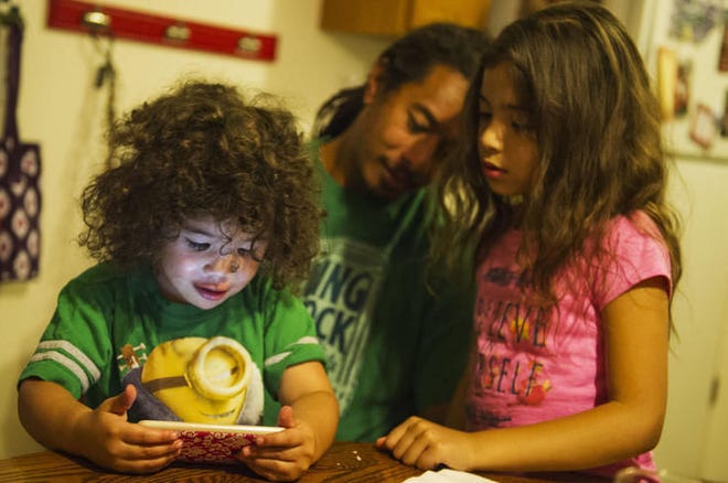 Maake Tuatonga watches a video with his dad, Ami, and sister, Maasi, at their home in West Valley City on Oct. 6.