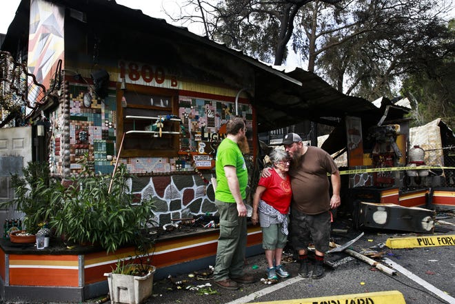 From left, Lightnin' Salvage employees Jordan Borstelmann, Judy Keathley and Danny Lore look at the remnants of their shop after Monday night's fire in Gainesville. Several employees and volunteers helped clean up the area. "I try to stay hopeful," Borstelmann said. (Andrea Cornejo/Staff photographer)
