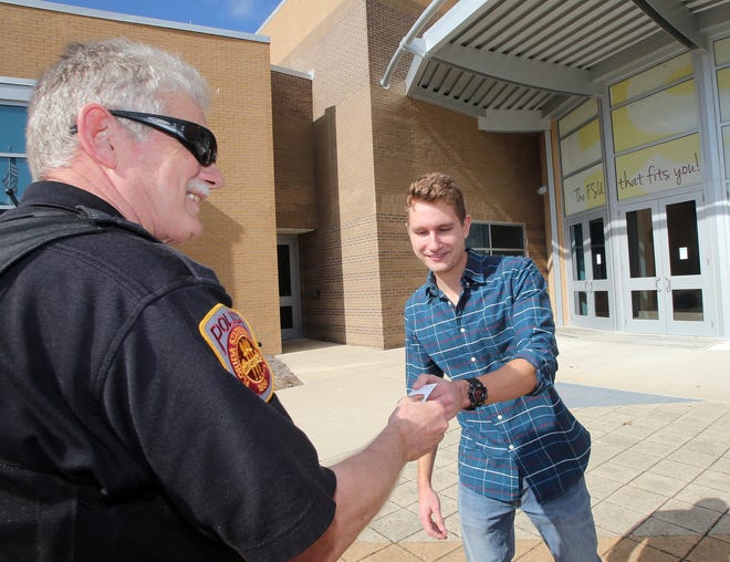 Officer Duane Gorey gives a free food coupon to Justice Wobser at Florida State University Panama City on Tuesday. ANDREW WARDLOW/THE NEWS HERALD