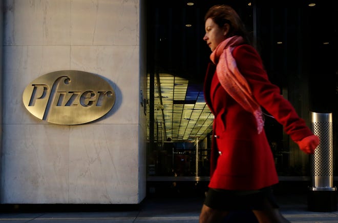 In this file photo, a woman passes Pfizer's world headquarters, in New York. British regulators fined U.S. drugmaker Pfizer and distributor Flynn Pharma a record 89.4 million pounds ($112.7 million) Wednesday for increasing the cost of an epilepsy drug by as much as 2,600 percent. AP Photo/Mark Lennihan, File
