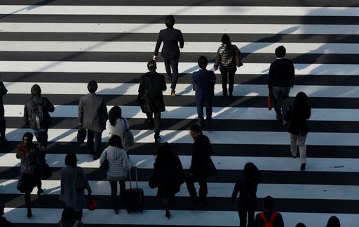 People walk on a pedestrian crossing in Tokyo, Thursday, Dec. 8, 2016. Japan's economy grew at a slower pace than earlier estimated in the July to September quarter, expanding at an annual pace of 1.3 percent. (AP Photo/Eugene Hoshiko)