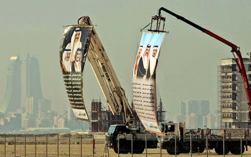 FILE- In this Jan. 6, 2010 file photo, construction cranes display huge banners with poetry welcoming Bahrain's leaders -- King Hamed bin Isa Al Khalifa, Prime Minister Prince Khalifa bin Salman Al Khalifa and Crown Prince Salman bin Hamed Al Khalifa, in Muharraq, Bahrain. In a slickly produced Islamic State group propaganda video, that surfaced as a Gulf Cooperation Council conference attended by British Prime Minister Theresa May ended on Wednesday, Dec. 7, 2016, IS called on its followers to launch attacks in Bahrain, including those targeting American military personnel stationed on the tiny island ahead of a visit by the U.S. defense secretary. (AP Photo/Hasan Jamali, File)