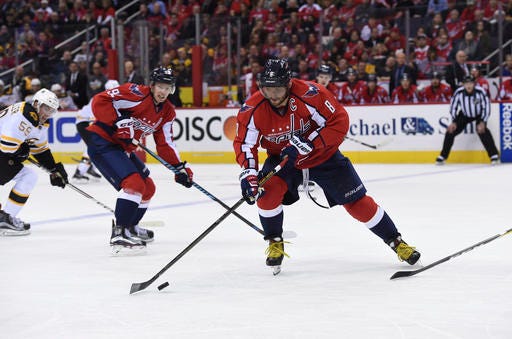 Washington Capitals left wing Alex Ovechkin (8), of Russia, handles the puck past Boston Bruins center Tim Schaller (59) and Washington Capitals center Evgeny Kuznetsov (92), of Russia, during second period of an NHL hockey game, Wednesday, Dec. 7, 2016, in Washington. (AP Photo/Molly Riley)