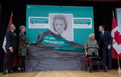 Bank of Canada Governor Stephen Poloz, left, Minister of Status of Women Patricia Hajdu, Minister of Finance Bill Morneau, right, and Wanda Robson unveil an image of Viola Desmond who will be featured on the new Canadian ten dollar bill during a ceremony in Gatineau, Quebec, Canada Thursday Dec. 8, 2016. Robson is Viola Desmond's sister. (Adrian Wyld/The Canadian Press via AP)