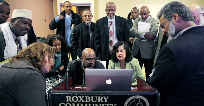 In this March 31, 2015 file photo, Muslim, Christian, minority and government leaders fix their eyes on a laptop screen showing a video as part of a federal pilot program called Countering Violent Extremism, at Roxbury Community College in Boston. The federally financed effort meant to stem the rise of homegrown extremists is finally underway in Massachusetts after years of delays and strong local opposition, and just weeks before a new administration takes over in the White House. The state picked three local organizations to use $210,000 in federal Countering Violent Extremism funding earlier this month. Seated at center right is Carmen Ortiz, U.S. Attorney for Massachusetts.