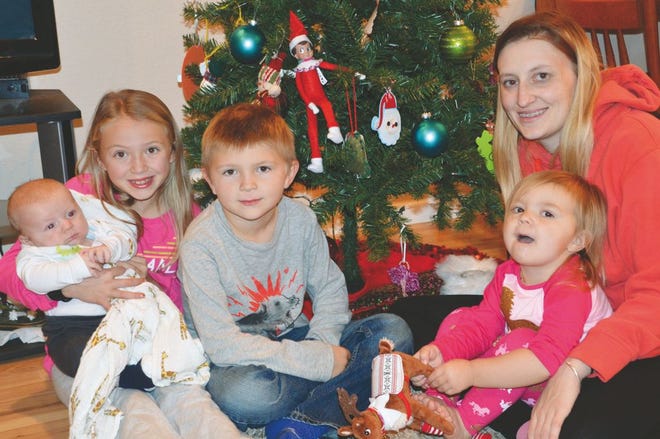 Brett and Natosha Gardner Scheuerman of Nevada have a busy household. But this time of the year, the children, (shown left to right) Gracie holding Oakley, Brody and Kinley being held by Natosha are excited to have their elf scout, Zippy, living with them in their home. Zippy, according to the children loves to hang out in their Christmas tree among other locations.