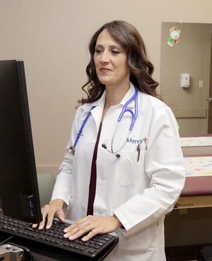 Dr. Ivelesse Dupree begins setting up the exam room for the first patient visit Tuesday, Dec. 6, 2016, after the ribbon-cutting and blessing for the new Mercy Clinic Pediatrics-Fort Smith Clinic, 3224 South 70th St. The new clinic offers more exam rooms, a larger lobby and conventient parking. JAMIE MITCHELL/TIMES RECORD