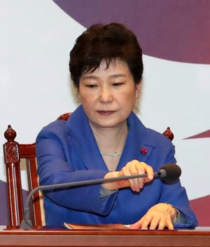 South Korean President Park Geun-hye adjusts a microphone during an emergency Cabinet meeting at the presidential office in Seoul, South Korea, Friday, Dec. 9, 2016. South Korean lawmakers earlier on Friday impeached Park, a stunning and swift fall for the country’s first female leader amid protests that drew millions into the streets in united fury. (Baek Sung-ryul/Yonhap via AP)