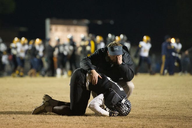 Havelock assistant coach Matt Handley consoles Havelock's Jeffrey Harris after the Rams lost 34-33 to Rocky Mount in the eastern 3A championship game Friday at Havelock High.