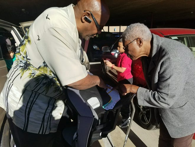 Community Health Action Network Executive Director Cornelius Page Jr. shows Victorville resident Annie Davis how to put in her brand new carseat for her grandson. Photo submitted by CHAN