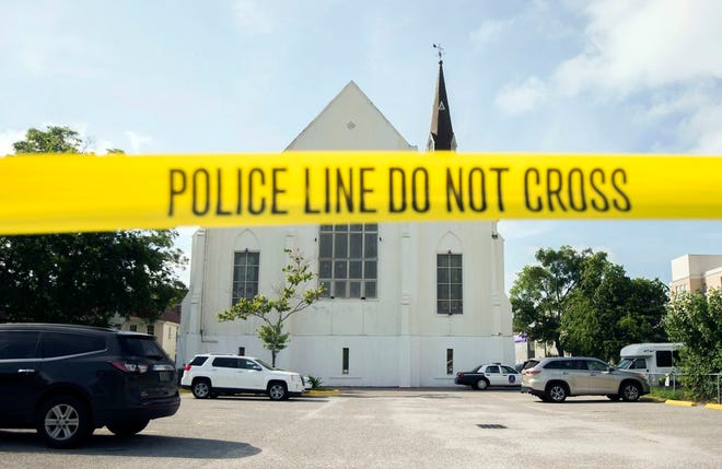 In this June 19, 2015 file photo, police tape surrounds the parking lot behind the AME Emanuel Church as FBI forensic experts work the crime scene, in Charleston, S.C.