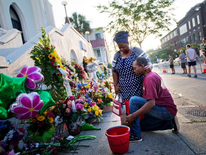 In this June 20, 2015, file photo, Allen Sanders, right, kneels next to his wife Georgette, both of McClellanville, S.C., as they pray at a sidewalk memorial in memory of the shooting victims in front of Emanuel AME Church in Charleston, S.C.