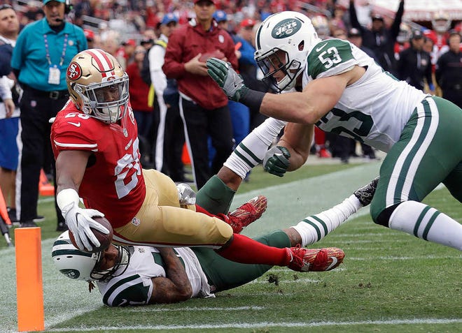 San Francisco running back Carlos Hyde scores a touchdown despite the efforts of New York Jets defenders Buster Skrine, bottom, and Mike Catapano on Sunday in Santa Clara, Calif. The Jets won in overtime, 23-17.