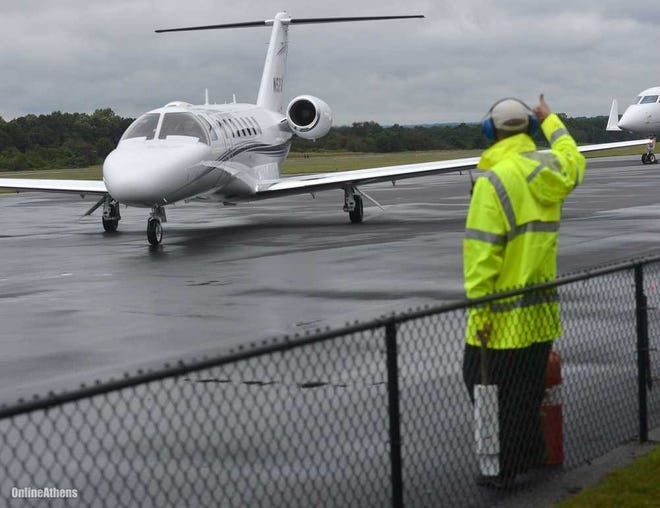 In this file photo, an Athens-Ben Epps Airport worker directs a jet to a parking spot on the airport ramp. The Athens-Ben Epps Airport Authority will ask Athens-Clarke County’s mayr and commission on Thursday to consider a $65,000 allocation to the airport to assist in efforts to attract commercial air service to Athens. (File photo)