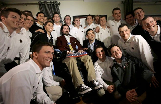 Former Boston College baseball captain Pete Frates, center left, and his brother Andrew, center right, pose for a photo with members of the Boston College baseball team after Pete was presented with the 2017 NCAA Inspiration Award, Tuesday, Dec. 13, 2016, at his home in Beverly, Mass. The NCAA honored Frates who inspired the ice bucket challenge that raised millions of dollars for Lou Gehrig's disease research. Frates was diagnosed with ALS in 2012.
