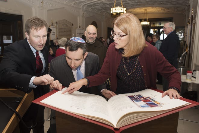 Examining the newly acquired copy of Saint John's Bible, the first handwritten and illuminated Bible produced in more than 500 years are, from left, Charles Zola, chair of the Division of Philosophy and Religious Studies at Mount Saint Mary College, Rabbi Philip Weintraub of Congregation Agudas Israel in Newburgh, and Barbara Petruzzelli, director of the Mount's Kaplan Family Library and Learning Center. Photo by Lee Ferris