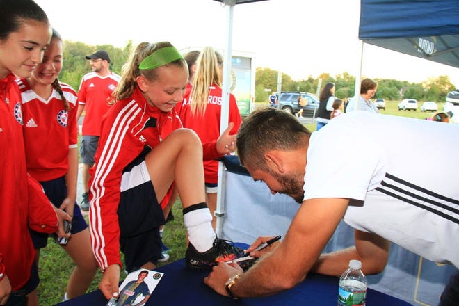 Defender Ken Tribbett signs the cleat of Marlena Ries at the Patriot FC soccer club's Philadelphia Union Night.