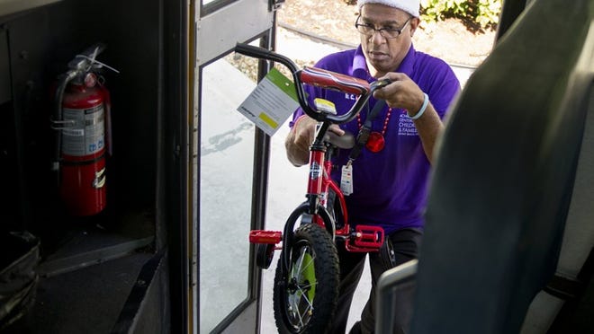 Achievement Centers for Children & Families activities coordinator Clayton Bell loads donated toys on to a bus Tuesday collected at the ‘Palm Beach Daily News.’