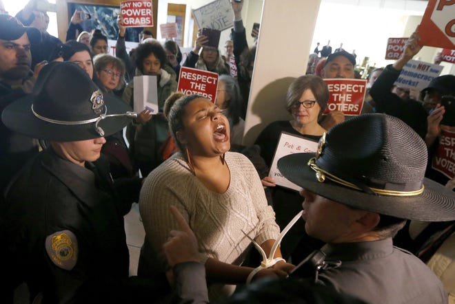 A protestor shouts as she is arrested outside the House gallery during a special session of the North Carolina General Assembly at the Legislative Building in Raleigh, N.C., Friday, Dec. 16, 2016. (Ethan Hyman/The News & Observer via AP)