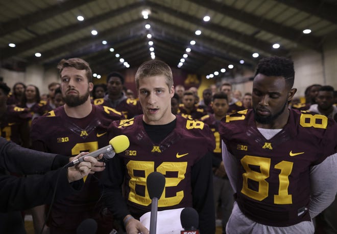 University of Minnesota wide receiver Drew Wolitarsky, flanked by quarterback Mitch Leidner, left, and tight end Duke Anyanwu stands in front of other team members as he reads a statement on behalf of the players in the Nagurski Football Complex in Minneapolis, Minn. The University of Minnesota football team will play in the Holiday Bowl, reversing a threat to boycott the game because of the suspension of 10 players accused of sexual assault. The players made the announcement at a news conference Saturday, Dec. 17, after a group of seniors from the team met with the board of regents, university President Eric Kaler and athletic director Mark Coyle on Friday night. STAR TRIBUNE VIA AP / JEFF WHEELER