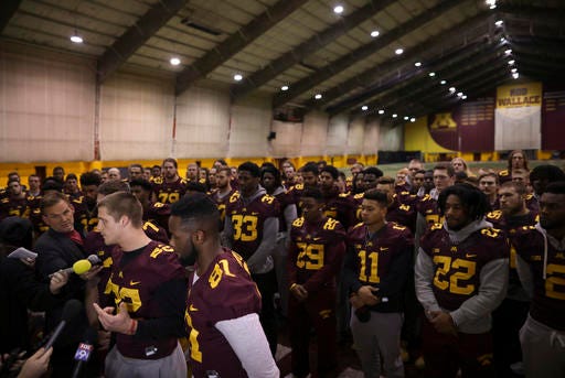 University of Minnesota wide receiver Drew Wolitarsky, flanked by quarterback Mitch Leidner, obscured behind Wolitarsky, and tight end Duke Anyanwu gestures as he stands in front of other team members while talking to reporters in the Nagurski Football Complex in Minneapolis, Minn., Thursday. The players delivered a defiant rebuke of the university's decision to suspend 10 of their teammates, saying they would not participate in any football activities until the school president and athletic director apologized and revoked the suspensions. If that meant they don't play in the upcoming Holiday Bowl against Washington State, they appeared poised to stand firm.