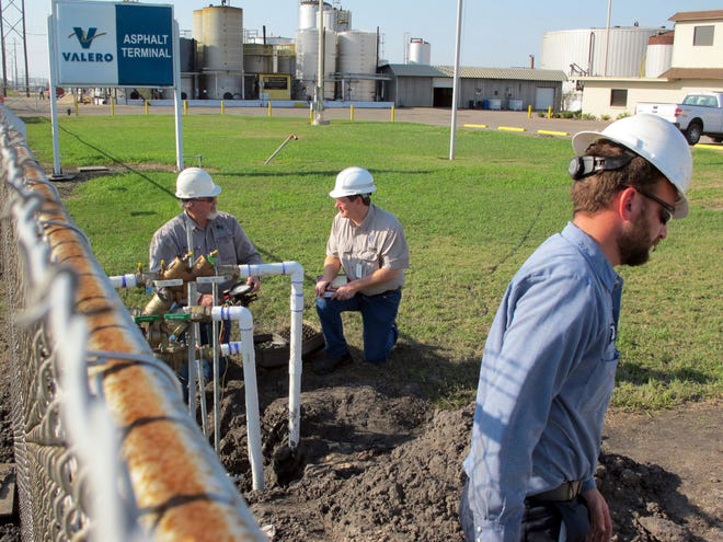 Unidentified men check pipes where Corpus Christi’s city-owned water main connects with an asphalt plant where a suspected chemical leak led to a city-wide ban on tapwater use, Saturday, Dec. 17, 2016, in Corpus Christi, Texas. The ban was been gradually eased and city officials expect the results of EPA tests on Sunday to determine it can be fully lifted. (AP Photo/Frank Bajak)