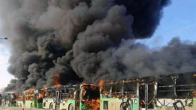 In this photo released by the Syrian official news agency SANA, smoke rises in green government buses, in Idlib province, Syria, Sunday, Dec. 18, 2016. Activists said, militants have burned at least five buses assigned to evacuate wounded and sick people from two villages in northern Syria. The incident could scuttle a wider deal that encompasses the evacuation of thousands of trapped rebel fighters and civilians from the last opposition foothold in east Aleppo.