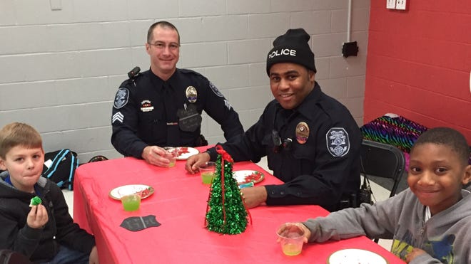 Sgt. J.L. Scher and Officer A.E. Johnson make new friends over punch and cookies at the Central YMCA on Friday. Photo by Jaimie Cline/Special to The Gazette