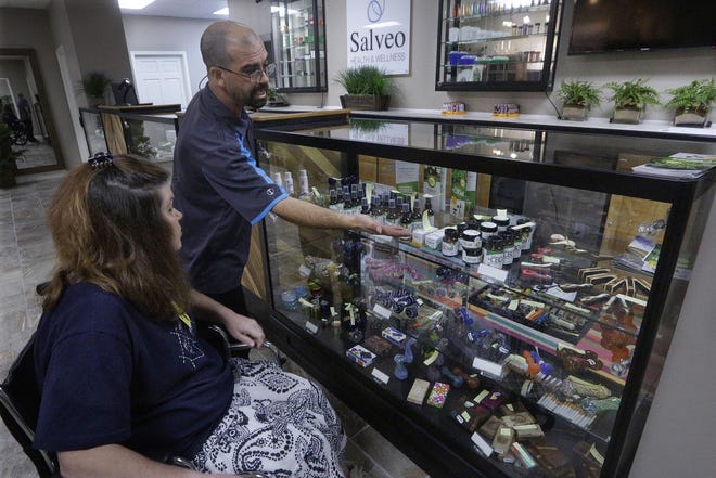 Shamay Flaharty of Lewiston, Illinois, who has multiple sclerosis and is hoping cannabis will help ease her pain and headaches, meets with Eric Sweatt, partner and manager of Salveo Health and Wellness, a licensed medical cannabis dispensary in Canton, Illinois. SETH PERLMAN/AP FILE