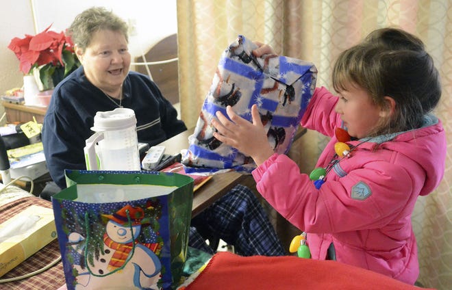 Marcella Rihely, a resident at Providence Care Center in Beaver Falls, gets a Christmas gift from Big Beaver Elementary School pupil Sadie Reitz, 6, on Tuesday.