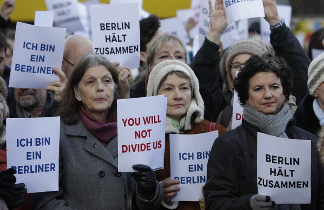 Singers hold posters "I am a Berliner", "you will not divide us" and "Berlin holds together" during a concert of a refugee choir and the choir of the memorial church in Berlin, Germany, Wednesday, Dec. 21, 2016, two days after a truck ran into a crowded Christmas market and killed several people. (AP Photo/Michael Sohn)