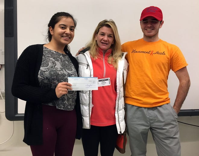 Oyster River High School students Roopa Bhat, left, and Ryan Coxen, right, present Kathy Kerrigan of Kathy For A Cure with a donation from the school's National Honor Society. Photo/Courtesy