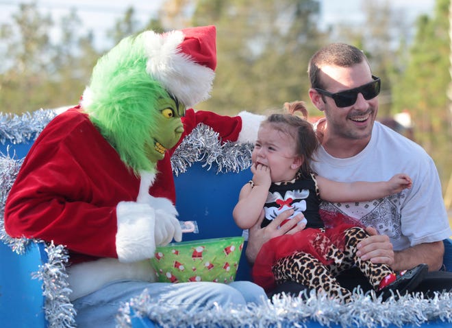 Tyler Worth holds Layla as she reacts to The Grinch during the annual Christmas with the Cops and Friends event on Saturday, Dec. 17, 2016, at the Lynn Haven Sports Complex in Lynn Haven, Fla. (Patti Blake /News Herald via AP)