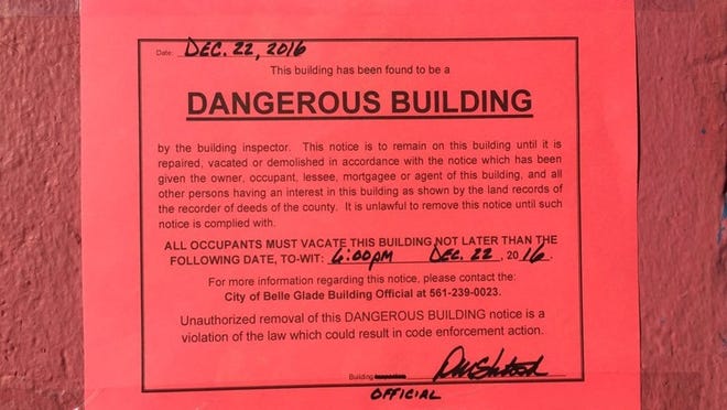 View of a sign from the City of Belle Glade calling the apartment building located on the 700 block of Martin Luther King Boulevard a dangerous building Thursday December 22, 2016 in Belle Glades. Belle Glade city officials are closing down the apartment complex until the owner can bring the facility up to code. The owner did not give the tenants the mandatory 90 day notice that today forty individuals will be homeless. Some of the families have been relocated to a motel in South Bay. Others will join family members in the area for the holidays.(Hannah Winston / The Palm Beach Post)